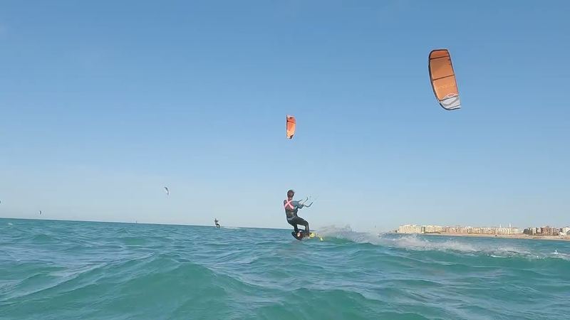 Kiter s oranžovým kitem na vlnkách před pobřežím Hurghady
